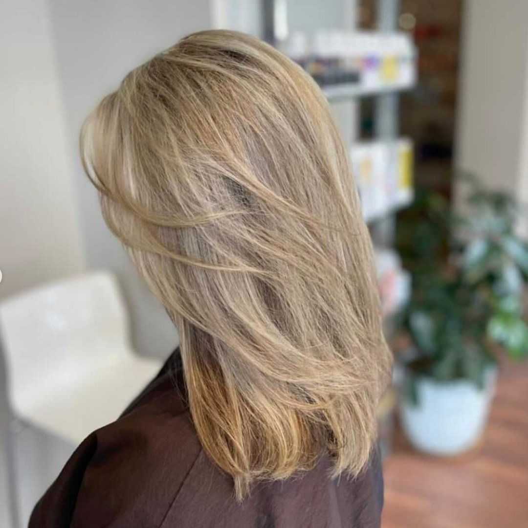 Blonde-haired person facing away, showcasing layered, shoulder-length hairstyle.